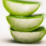 close up view of cut aloe vera leaves on white surface